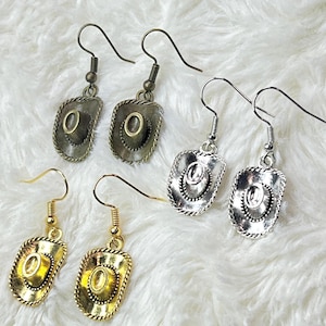 May include: Three pairs of dangle earrings with a cowboy hat charm. The earrings are available in gold, silver, and bronze.