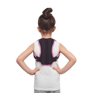 May include: A black posture corrector with pink edging is worn by a person. The posture corrector is designed to support the back and shoulders. The person is wearing a white vest top. The background is plain white.