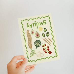Puede incluir: Una tarjeta amarilla con un borde verde y la palabra "Antipasti" en letras verdes. La tarjeta presenta ilustraciones de varios ingredientes de antipasti italianos, incluyendo pan, alcachofa, aceitunas, higos, tomates y lim&oacute;n.