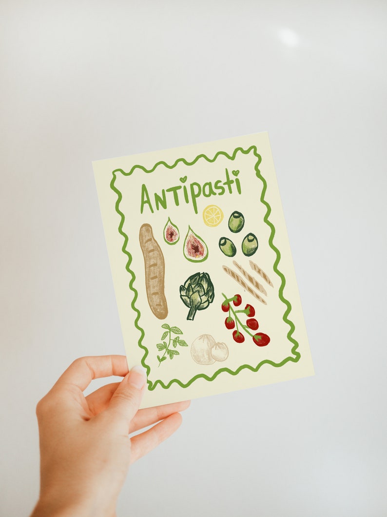 Puede incluir: Una tarjeta amarilla con un borde verde y la palabra "Antipasti" en letras verdes. La tarjeta presenta ilustraciones de varios ingredientes de antipasti italianos, incluyendo pan, alcachofa, aceitunas, higos, tomates y lim&oacute;n.