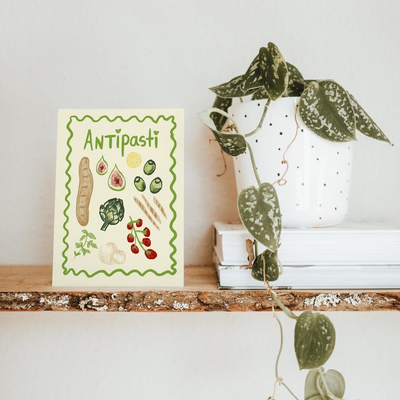 Puede incluir: Una tarjeta amarilla con un borde verde y la palabra "Antipasti" en letras verdes. La tarjeta presenta ilustraciones de varios ingredientes de antipasti italianos, incluyendo alcachofa, aceitunas, pan, higos y tomates.