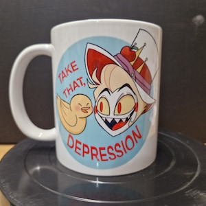 May include: White ceramic mug with a cartoon illustration of a character with red hair, a crown, and a red and white hat. The character is holding a yellow bird and the text "Take that, Depression" is printed on the mug.