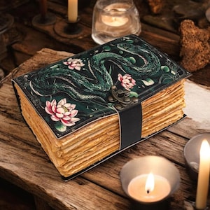 Può includere: Un diario rilegato in pelle verde scuro con un design a serpente e fiori. Il diario ha una chiusura in ottone ed è aperto per rivelare pagine invecchiate e ingiallite.