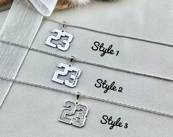 May include: Three silver necklaces with a pendant featuring the number 23. The first necklace has a plain pendant, the second has the word "JORDAN" engraved on the pendant, and the third has the word "JORDAN" engraved on the pendant and a black outline around the number. The necklaces are labeled "Style 1", "Style 2", and "Style 3".