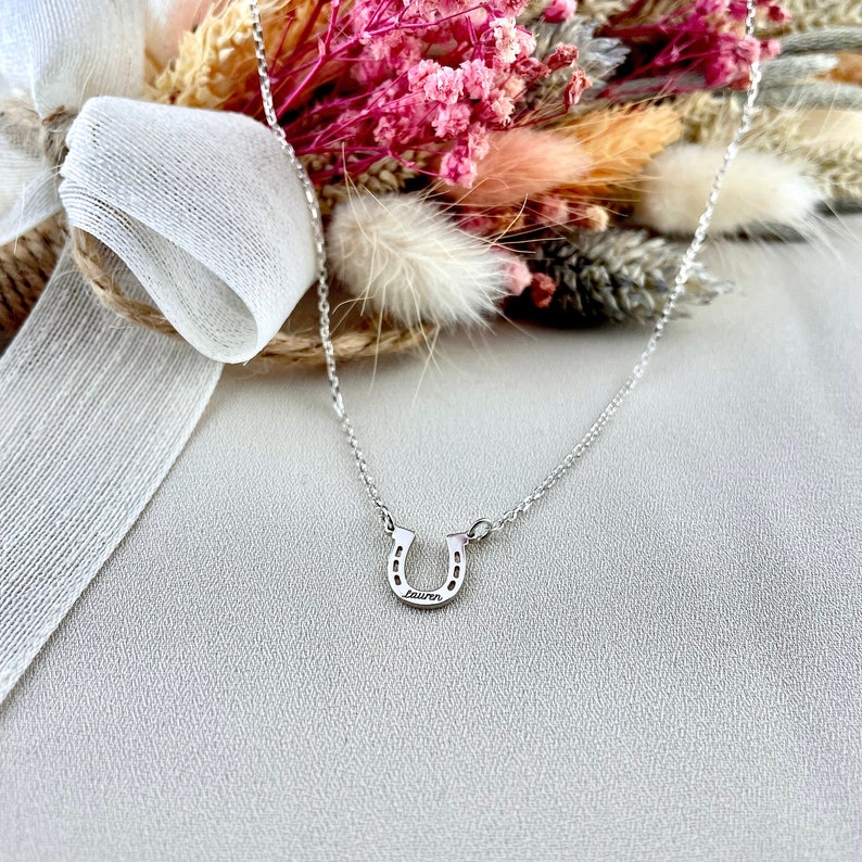 Pu&ograve; includere: Una collana d'argento a forma di ferro di cavallo con il nome "Lauren" inciso sul ferro di cavallo.