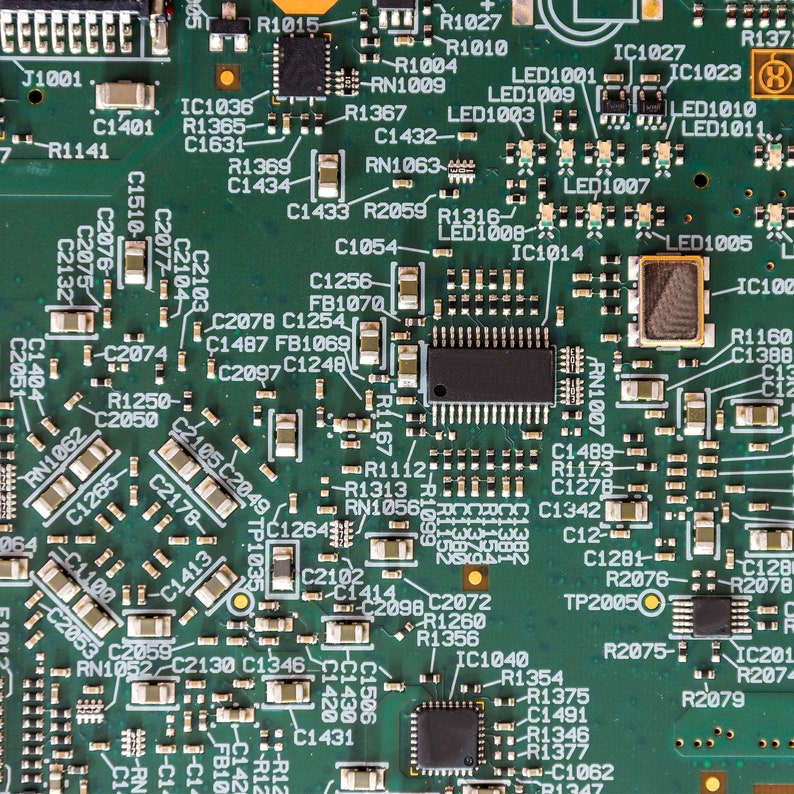 Pode incluir: Uma placa de circuito impresso verde com v&aacute;rios componentes eletr&ocirc;nicos, incluindo resistores, capacitores, circuitos integrados e LEDs. A placa &eacute; etiquetada com n&uacute;meros e letras, que indicam os diferentes componentes e suas conex&otilde;es.