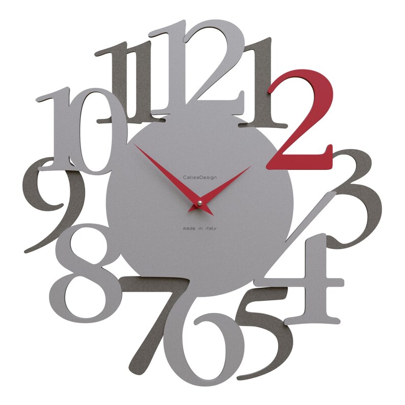 May include: A modern wall clock with a gray face and red hands. The numbers are in a unique, overlapping design, with the number 2 in red. The clock face has the text "CaleoDesign" and "made in italy".