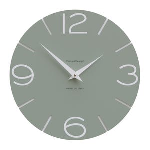 Può includere: Un orologio da parete rotondo di colore verde salvia con numeri e lancette bianchi. Il quadrante dell'orologio ha il testo "Callie's Design" e "made in Italy".