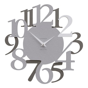 May include: A modern wall clock with a gray textured face and cut-out numbers in varying shades of gray. The clock hands are white, and the text "CarlaDesign" and "made in italy" are visible.