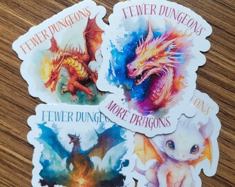 May include: Four white stickers with watercolor illustrations of dragons. The stickers have the text "Fewer Dungeons, More Dragons" on them.