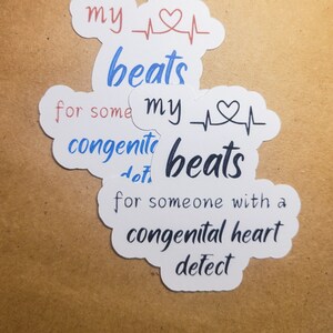 May include: Three white stickers with a heart beat symbol and the text "my beats for some with a congenital heart detect".