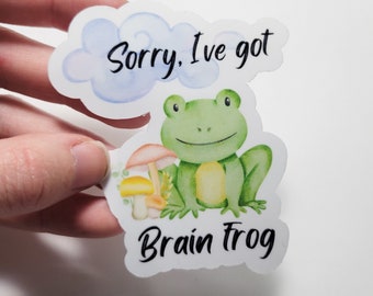 May include: A sticker with a green frog sitting on a mushroom. The sticker says "Sorry, I've got Brain Frog" in a cloud above the frog.
