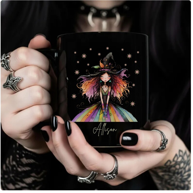 Puede incluir: Taza de cer&aacute;mica negra con una ilustraci&oacute;n de una bruja con pelo y vestido arco&iacute;ris. La taza tiene el nombre "Allison" en cursiva. Estrellas dispersas alrededor de la bruja.