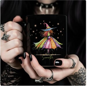 Puede incluir: Taza de cer&aacute;mica negra con una colorida ilustraci&oacute;n de acuarela de una bruja con un vestido y sombrero caprichosos. El nombre de la bruja, Samantha, est&aacute; escrito debajo. La taza es sostenida por una persona con esmalte de u&ntilde;as negro.