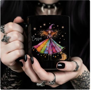 Puede incluir: Taza de cer&aacute;mica negra con una ilustraci&oacute;n de una bruja con un vestido arco&iacute;ris, sosteniendo una escoba. La taza tiene el nombre "Cassie" en escritura cursiva y est&aacute; decorada con estrellas. Un regalo &uacute;nico para los fan&aacute;ticos de la fantas&iacute;a y la magia.