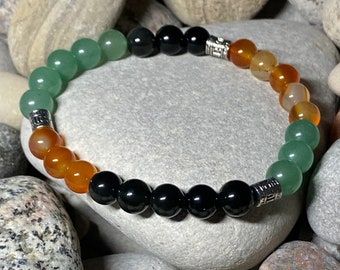 May include: A green, black, and orange beaded bracelet with silver accents. The bracelet is made of natural stones and is a popular choice for those seeking a stylish and meaningful accessory.