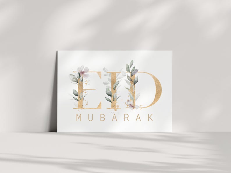May include: A white card with the words "Eid Mubarak" in gold lettering with floral accents. The letters are outlined in gold and have watercolor flowers and leaves in shades of green and pink.