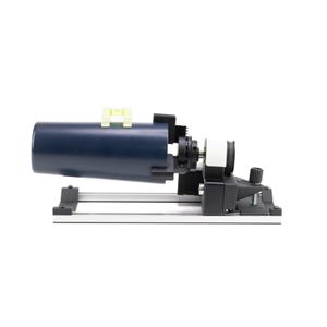 Può includere: Un oggetto cilindrico blu scuro con una livella gialla, montato su una base nera e argentata. Il dispositivo ha vari componenti meccanici e una manopola nera. Lo sfondo è bianco.