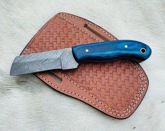 May include: A blue and silver Damascus steel knife with a blue wood handle and a leather sheath.