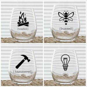 Peut inclure: Quatre verres à vin en verre transparent avec des motifs graphiques noirs et du texte. Les motifs comprennent un feu de camp avec le texte "[toasted]", une abeille avec le texte "[buzzed]", un marteau avec le texte "[hammered]" et une ampoule avec le texte "[lit]".
