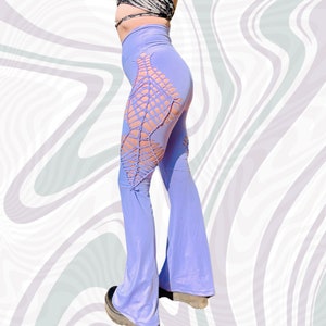 May include: Purple bell bottom pants with a cut-out design on the side. The pants are made of a soft, stretchy fabric.