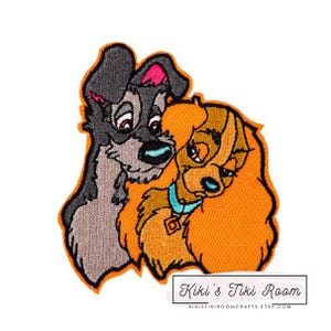 Op de afbeelding: Geborduurde patch met Lady en de Tramp, een klassiek Disney-koppel. De patch toont Lady, een bruine en witte cocker spaniel, met haar hoofd rustend op Tramp, een zwarte en grijze zwerfhond. De patch is op een oranje achtergrond.