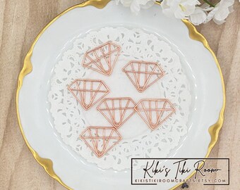 May include: Six rose gold diamond-shaped paper clips on a white doily on a white plate with a gold rim. The plate has the text "Kiki's Tiki Room" and "kikistikirroomcrafts.etsy.com" printed on it.