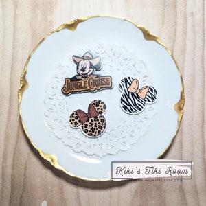 May include: Three Disney-themed iron-on patches. One features Mickey Mouse wearing a cowboy hat and the words "Jungle Cruise". The other two are Mickey Mouse ears, one with a zebra print and the other with a leopard print.