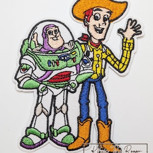 Peut inclure: Écusson brodé représentant les personnages de Buzz l'Éclair et Woody du film Toy Story. Buzz est dans sa combinaison spatiale verte et blanche, et Woody porte une chemise jaune, un jean bleu et un chapeau de cow-boy. Le patch a une bordure blanche.