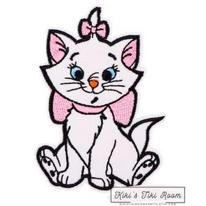 May include: White embroidered iron-on patch of a cartoon cat with pink bow and collar. The cat is sitting with its tail curled around its legs. The patch is for sewing or ironing onto fabric.