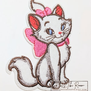 May include: An embroidered patch featuring a white kitten with blue eyes, pink inner ears, and a large pink bow on its head and neck. The kitten has brown outlines and a fluffy tail. The text Kiki's Tiki Room KIKISTIKIROOMCRAFTS.ETSY.COM is visible.