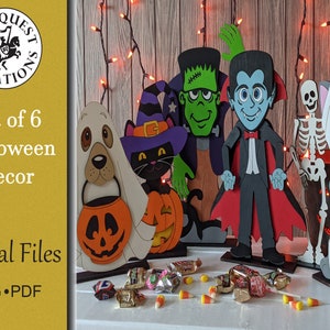 Op de afbeelding: Set van zes houten Halloween-decoraties, waaronder een spookhond, zwarte kat, Frankenstein, vampier, skelet en mummiekat. De figuren zijn in verschillende kleuren geschilderd. Er zijn ook snoepjes te zien.