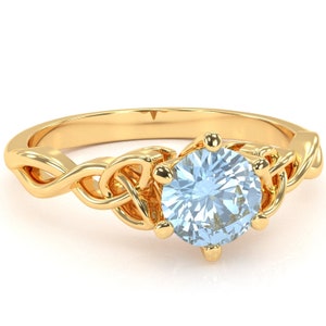 May include: A gold ring with a delicate, twisted band and a large, round, light blue gemstone in the center.