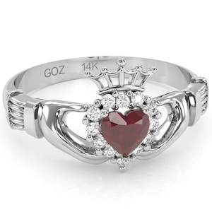 May include: A 14K white gold Claddagh ring with a red heart, a crown, and a halo of diamonds. The ring is engraved with "GOZ".