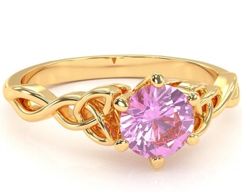 May include: A gold ring with a pink gemstone set in a Celtic knot design.
