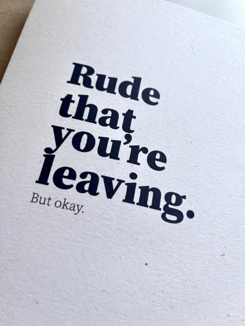 May include: A white card with the text "Rude that you're leaving. But okay." printed in a bold, black font. The card has a textured surface and a minimalist design, suitable for various occasions.