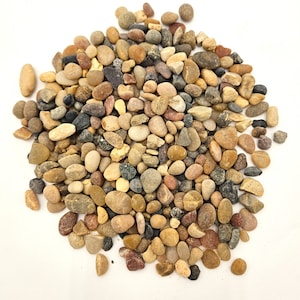 May include: A pile of small, smooth, natural stones in various shades of brown, gray, and red. The stones are a mix of shapes and sizes, and they are arranged in a random pattern.