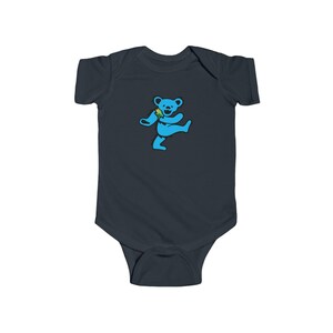 May include: A dark gray baby bodysuit featuring a light blue dancing bear graphic. The bear is holding a green and yellow object. The bodysuit is made of soft material and has short sleeves.