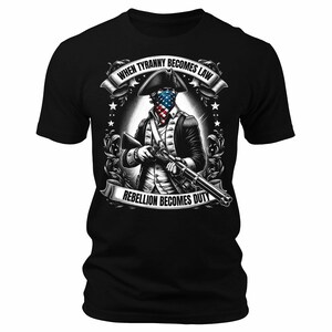 May include: Black t-shirt with a graphic of a man in a colonial uniform holding a rifle. The graphic includes the text "When Tyranny Becomes Law Rebellion Becomes Duty".