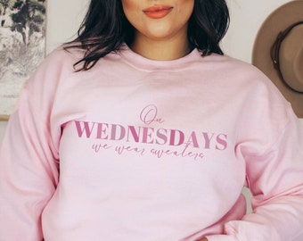 May include: A pink sweatshirt with the text "On Wednesdays we wear sweaters" in pink lettering.