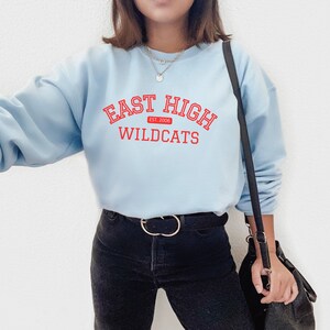 May include: A light blue sweatshirt with the text "East High Est. 2006 Wildcats" in red.
