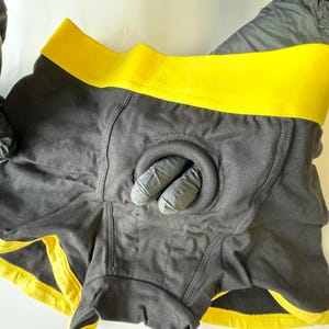 May include: Black underwear with a yellow waistband and a circular opening at the front.