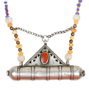 May include: A silver-toned metal pendant necklace featuring a triangular top section with a central oval red stone and a cylindrical base. The necklace includes strands of multi-colored beads in blue, red, orange, and white, connected by silver chains.