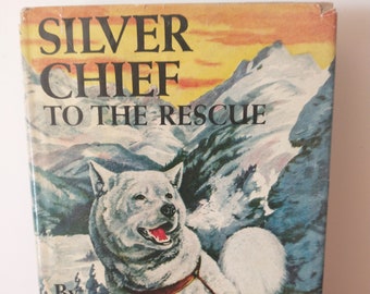 May include: A vintage book cover featuring a white dog with a red collar, titled "Silver Chief to the Rescue" by Jack O'Brien. The book is part of the "Famous Dog Stories" series.