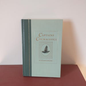 May include: A green hardcover book with gold lettering titled "Captains Courageous" by Rudyard Kipling. The cover features a black and white illustration of a ship.