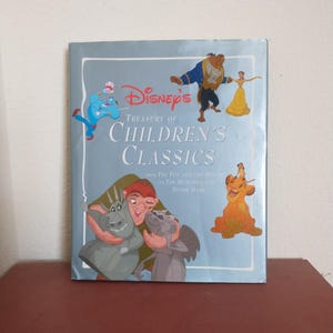 May include: A silver book cover with the title "Disney's Treasury of Children's Classics" and images of characters from Disney movies, including Aladdin, Beauty and the Beast, The Hunchback of Notre Dame, and The Lion King.