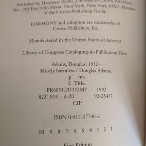 Puede incluir: Una portada de libro con el t&iacute;tulo "Mayormente inofensivo" de Douglas Adams. El libro forma parte de la serie "La gu&iacute;a del autoestopista gal&aacute;ctico". La portada es blanca con texto negro y una ilustraci&oacute;n en blanco y negro de una nave espacial.