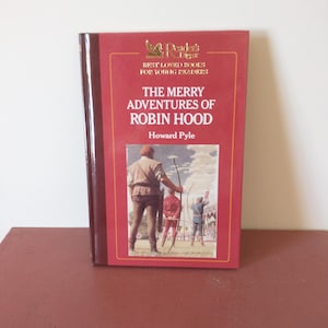 May include: A red hardcover book with a gold illustration of a bird on the front cover. The title is "The Merry Adventures of Robin Hood" by Howard Pyle. The book is part of the Reader's Digest Best Loved Books for Young Readers series.