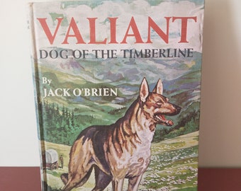 May include: A vintage book cover with a brown and black German Shepherd dog standing in a field of sheep. The title of the book is "Valiant Dog of the Timberline" by Jack O'Brien. The book is part of the "Famous Dog Stories" series.