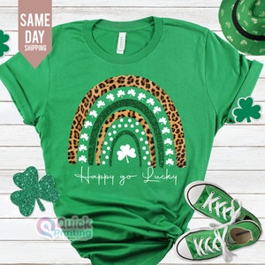 May include: Green t-shirt with a rainbow design featuring leopard print and shamrocks. The rainbow has white polka dots and glitter. The text "Happy go Lucky" is written below the rainbow.